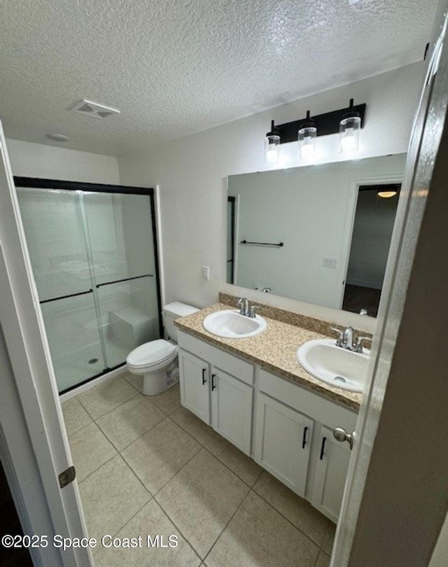 bathroom with toilet, vanity, tile patterned flooring, a textured ceiling, and an enclosed shower