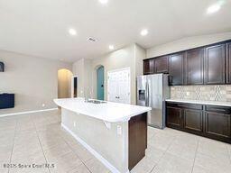 kitchen featuring tasteful backsplash, a center island with sink, sink, light tile patterned floors, and stainless steel fridge