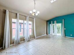 empty room with vaulted ceiling, an inviting chandelier, and light tile patterned flooring