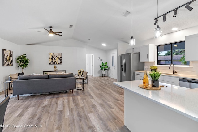 kitchen featuring pendant lighting, white cabinets, lofted ceiling, stainless steel appliances, and sink