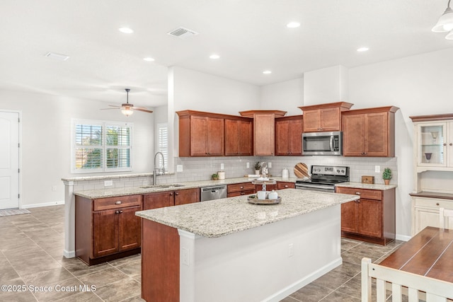 kitchen with tasteful backsplash, sink, a center island, light stone counters, and stainless steel appliances