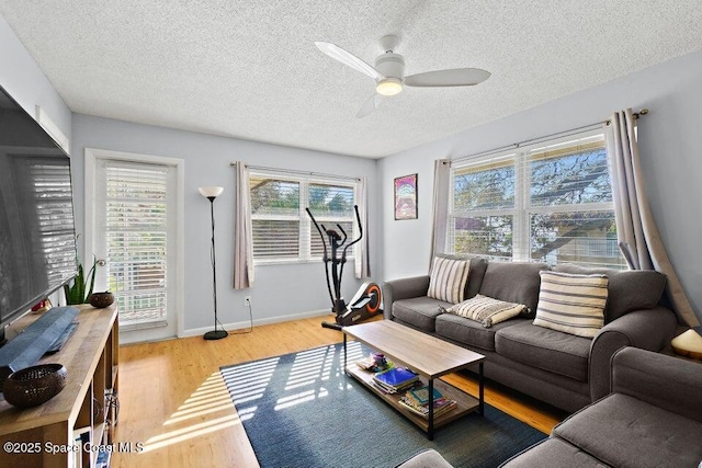 living room with ceiling fan, a textured ceiling, and light hardwood / wood-style flooring