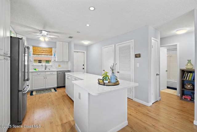 kitchen featuring white cabinetry, stainless steel appliances, decorative backsplash, a textured ceiling, and a center island