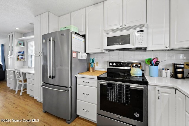 kitchen featuring decorative backsplash, white cabinetry, and appliances with stainless steel finishes