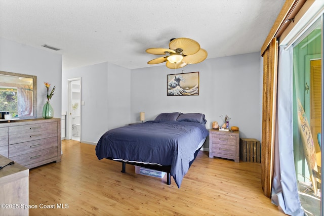 bedroom featuring ceiling fan, connected bathroom, light hardwood / wood-style flooring, and a textured ceiling