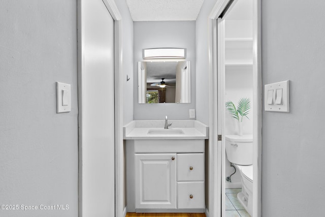 bathroom with toilet, vanity, and a textured ceiling