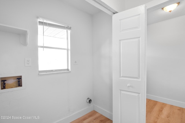 clothes washing area with a healthy amount of sunlight, hardwood / wood-style flooring, and hookup for a washing machine