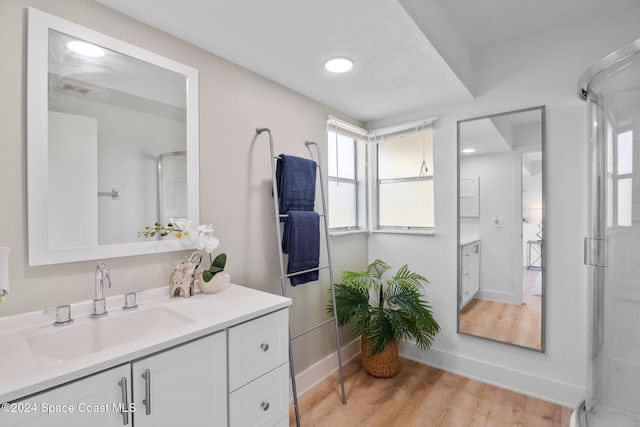 bathroom with a shower with door, hardwood / wood-style floors, and vanity