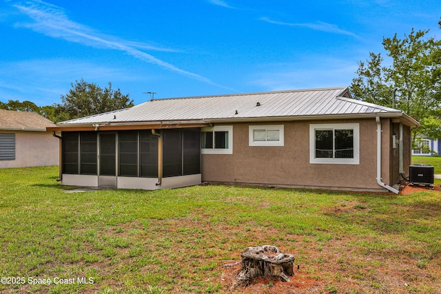 rear view of house with central AC unit, a yard, and a sunroom