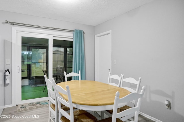 dining space with hardwood / wood-style floors and a textured ceiling