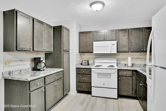 kitchen with white appliances, dark brown cabinets, and light hardwood / wood-style floors