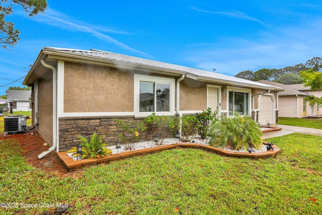 exterior space featuring a garage, a yard, and central AC