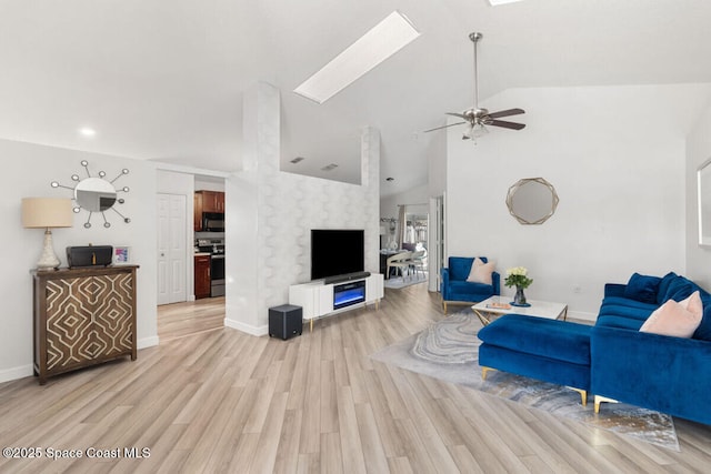 living room featuring ceiling fan, lofted ceiling with skylight, and light hardwood / wood-style flooring