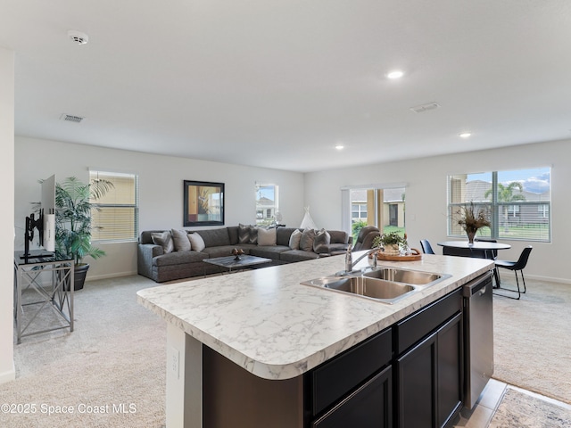 kitchen featuring sink, light colored carpet, dishwasher, and a center island with sink