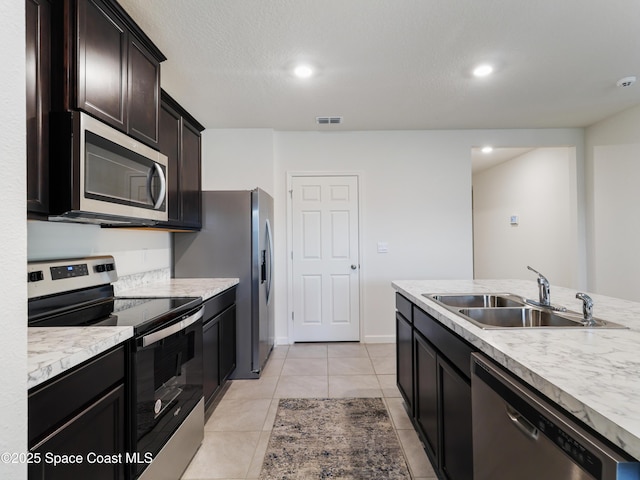 kitchen featuring dark brown cabinetry, sink, a textured ceiling, light tile patterned floors, and appliances with stainless steel finishes