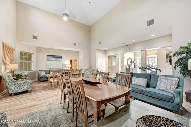 dining room featuring a towering ceiling and light hardwood / wood-style flooring