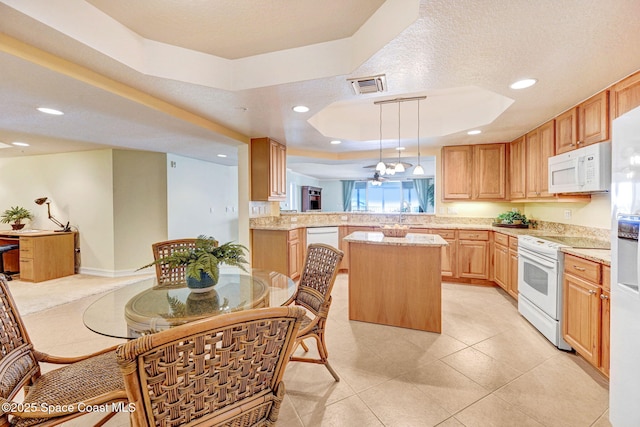 kitchen featuring light stone counters, decorative light fixtures, a tray ceiling, kitchen peninsula, and white appliances