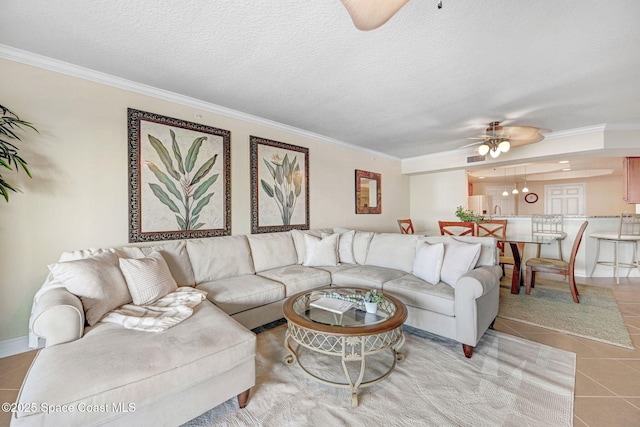 living room featuring light tile patterned floors, a textured ceiling, ornamental molding, and ceiling fan