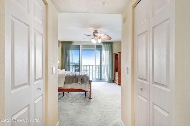 bedroom with ceiling fan, access to exterior, carpet floors, and a textured ceiling