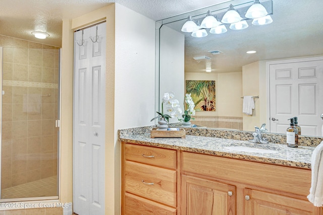 bathroom featuring vanity, a shower with door, and a textured ceiling