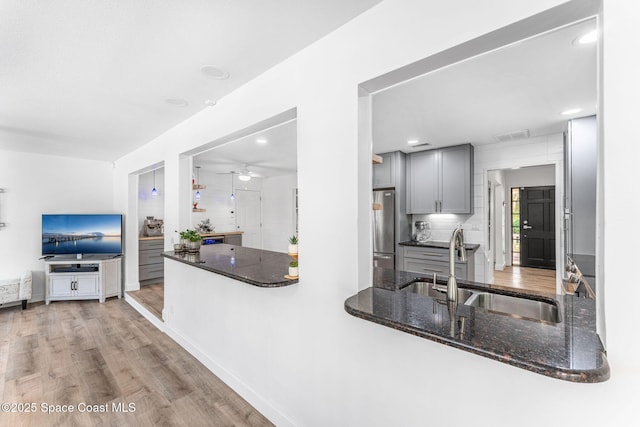 kitchen with gray cabinets, sink, stainless steel fridge, and kitchen peninsula