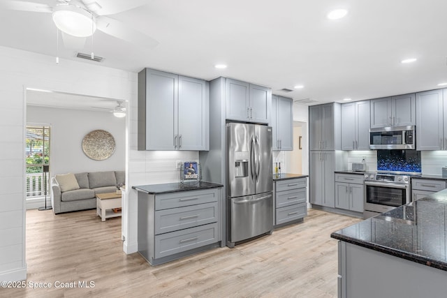 kitchen with light hardwood / wood-style flooring, appliances with stainless steel finishes, gray cabinets, ceiling fan, and decorative backsplash