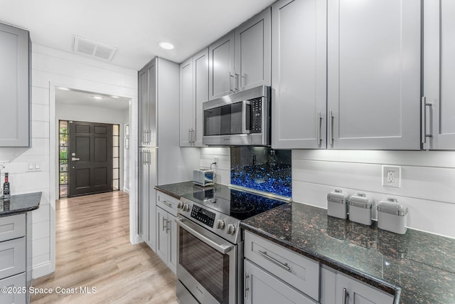 kitchen with gray cabinets, dark stone counters, and appliances with stainless steel finishes