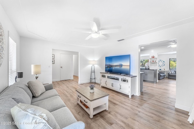 living room featuring ceiling fan, light hardwood / wood-style floors, and a wealth of natural light