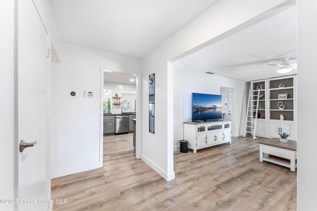 living room with ceiling fan, built in features, and light wood-type flooring