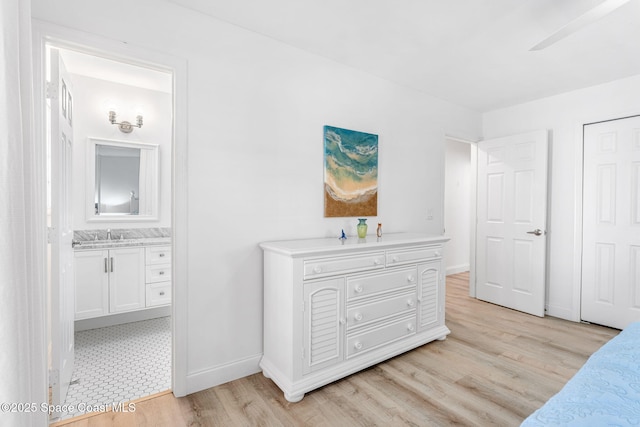 bedroom with sink, ensuite bath, light hardwood / wood-style flooring, and ceiling fan