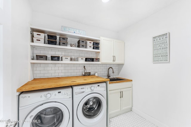 clothes washing area with cabinets, sink, and washing machine and clothes dryer