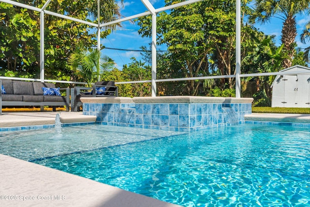 view of pool with pool water feature, an outdoor hangout area, glass enclosure, and a shed