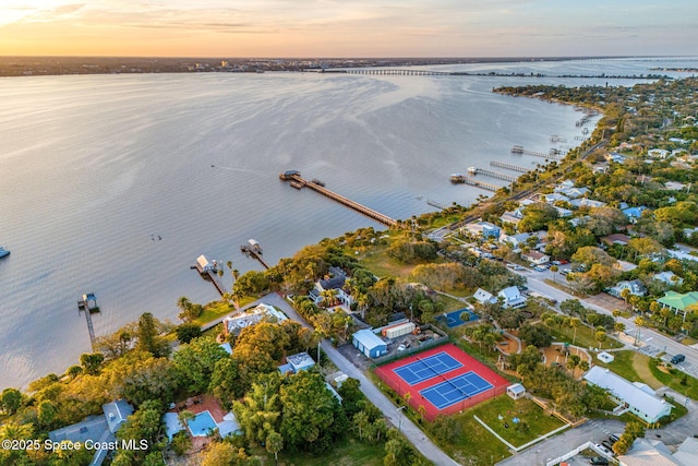 aerial view at dusk featuring a water view