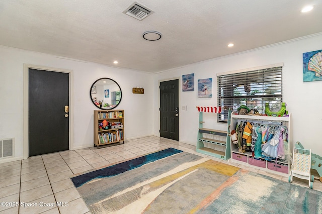 entryway featuring light tile patterned flooring, ornamental molding, and a textured ceiling