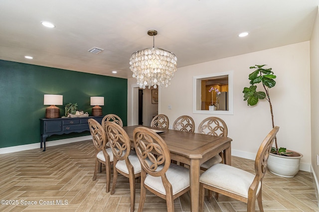 dining space with light parquet flooring and a notable chandelier