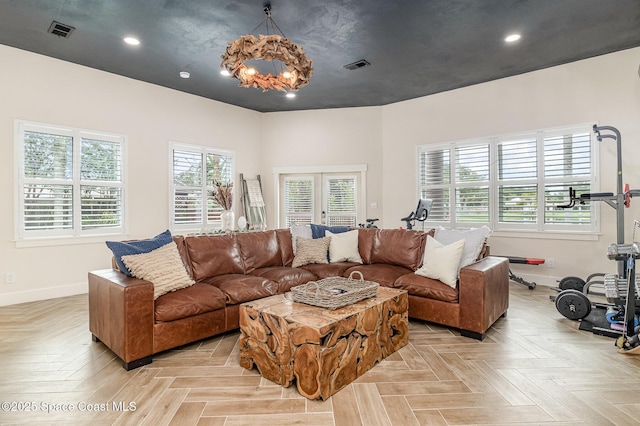 living room with light parquet flooring, a chandelier, and french doors