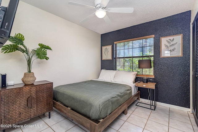 tiled bedroom with ceiling fan and a textured ceiling