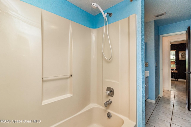 bathroom featuring shower / bathing tub combination, tile patterned flooring, and a textured ceiling