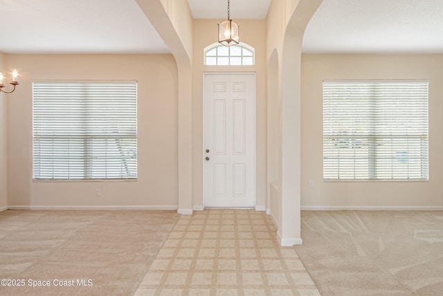 entryway featuring light carpet and a notable chandelier