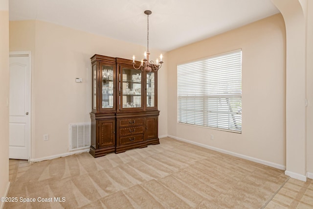 unfurnished dining area featuring light colored carpet and a notable chandelier