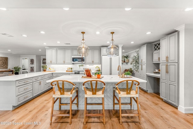 kitchen featuring gray cabinetry, range, white refrigerator, a kitchen breakfast bar, and pendant lighting