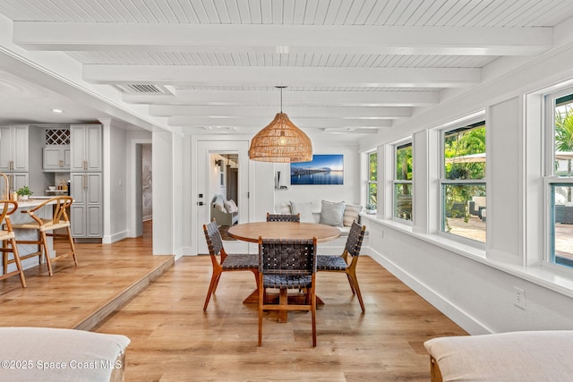 dining space with beam ceiling and light hardwood / wood-style flooring