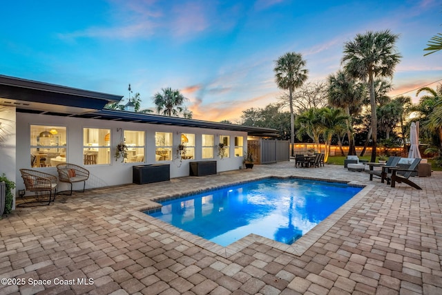 pool at dusk with a patio area