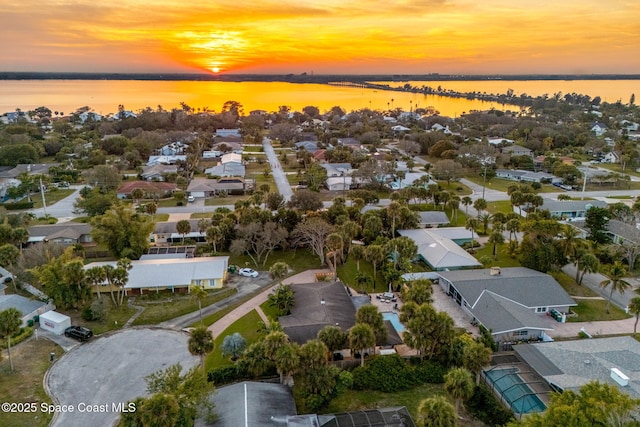 aerial view at dusk featuring a water view