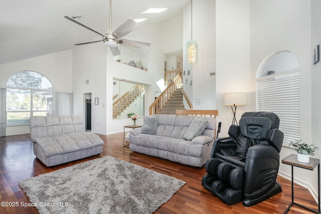 living room with dark hardwood / wood-style flooring, a skylight, high vaulted ceiling, and a textured ceiling