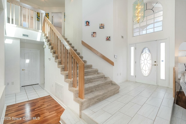 entryway featuring a high ceiling, light tile patterned floors, and a chandelier