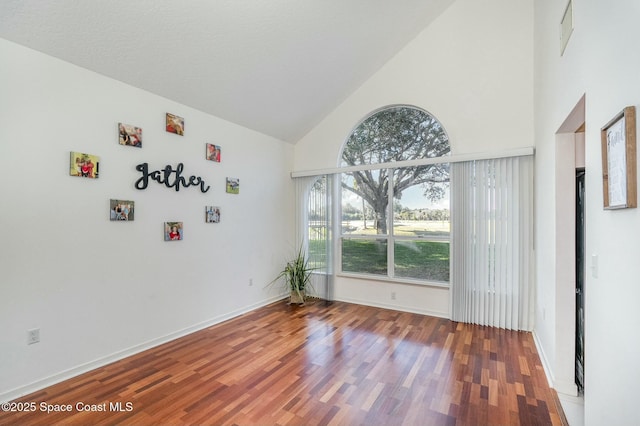 unfurnished dining area featuring wood-type flooring and high vaulted ceiling