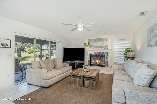 living room with a tile fireplace, light tile patterned floors, and ceiling fan