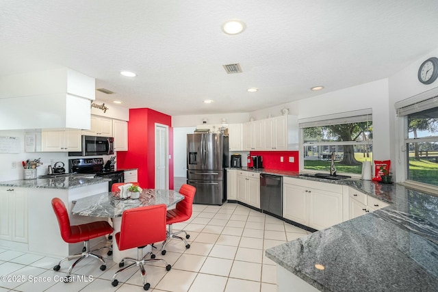 kitchen with stainless steel appliances, plenty of natural light, sink, and a breakfast bar area