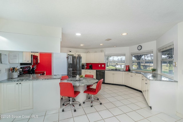 kitchen featuring appliances with stainless steel finishes, sink, a breakfast bar area, dark stone counters, and kitchen peninsula